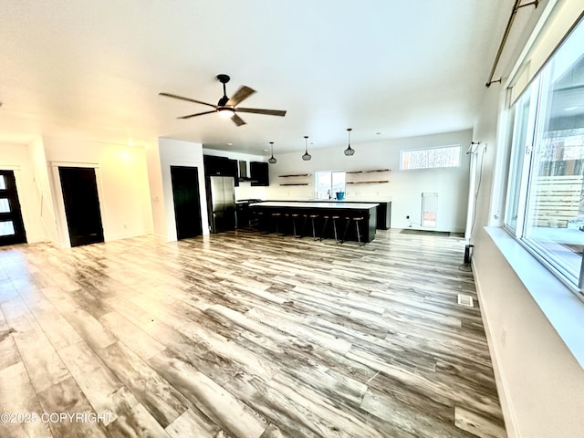 unfurnished living room featuring ceiling fan and wood-type flooring