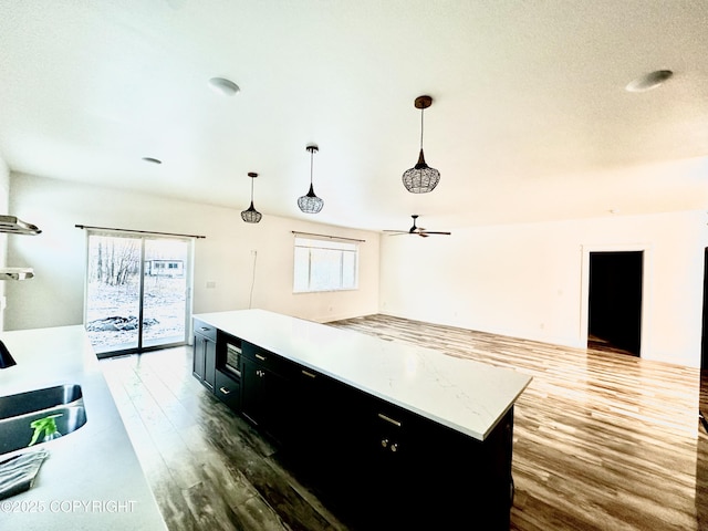 kitchen with sink, a kitchen island, pendant lighting, and hardwood / wood-style flooring