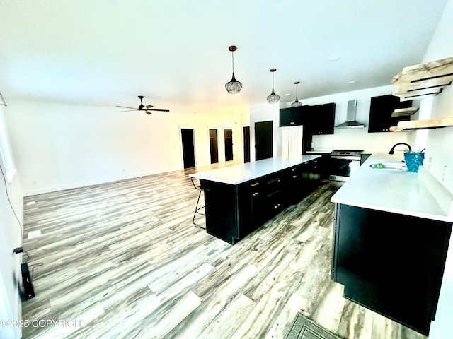 kitchen with appliances with stainless steel finishes, sink, wall chimney range hood, decorative light fixtures, and a kitchen island