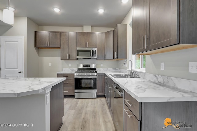 kitchen with appliances with stainless steel finishes, sink, and light hardwood / wood-style flooring