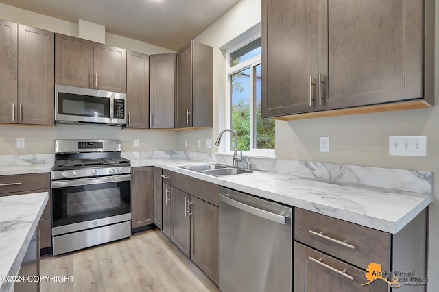 kitchen with stainless steel appliances, sink, dark brown cabinetry, and light wood-type flooring