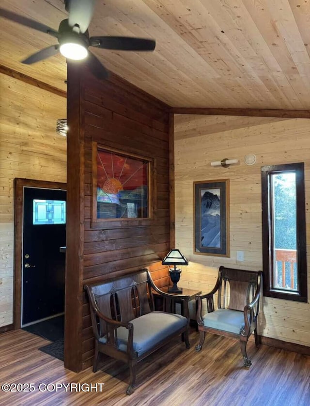 sitting room featuring wood ceiling, wooden walls, ceiling fan, wood-type flooring, and vaulted ceiling