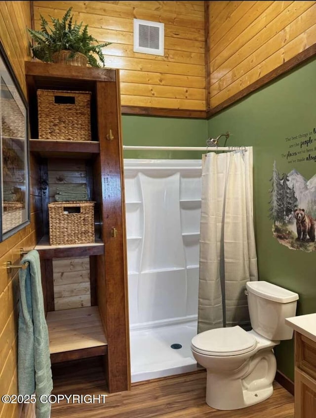 full bathroom with visible vents, toilet, wood finished floors, vanity, and a shower stall