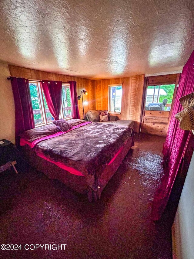 bedroom featuring a textured ceiling, wood walls, and carpet flooring