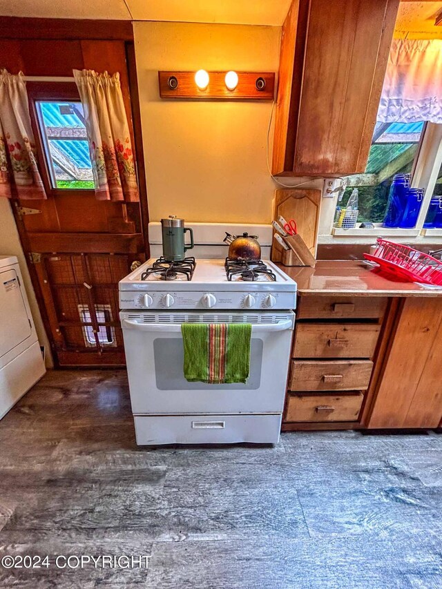 kitchen featuring washer / clothes dryer, dark hardwood / wood-style flooring, and white gas stove