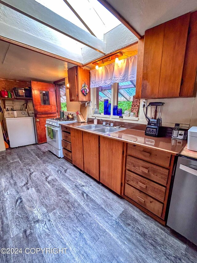 kitchen with a skylight, dishwasher, high end stove, independent washer and dryer, and sink