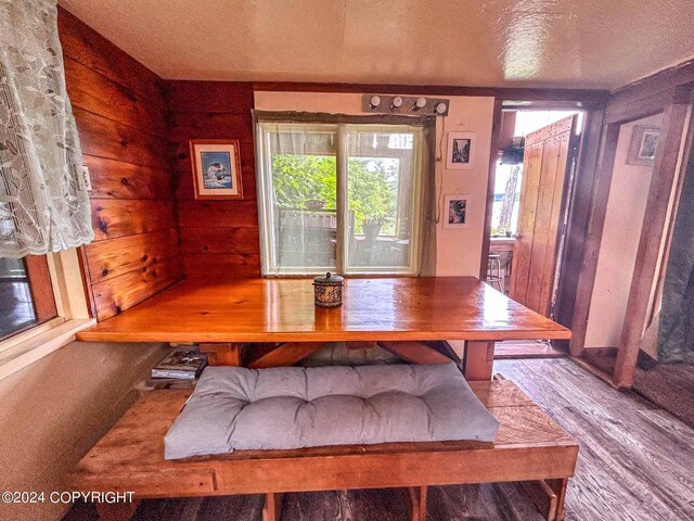 dining room featuring a textured ceiling, wood-type flooring, and wood walls