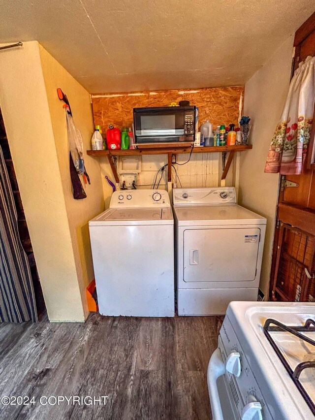 clothes washing area with dark wood-type flooring, washing machine and dryer, and a textured ceiling