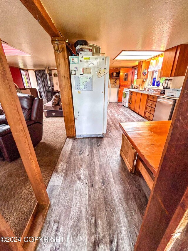 kitchen with white refrigerator, wood-type flooring, stainless steel range oven, and a textured ceiling