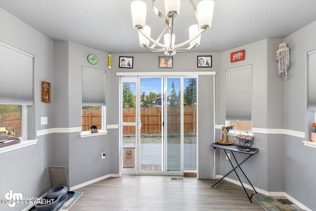 doorway to outside featuring hardwood / wood-style floors, plenty of natural light, and a notable chandelier