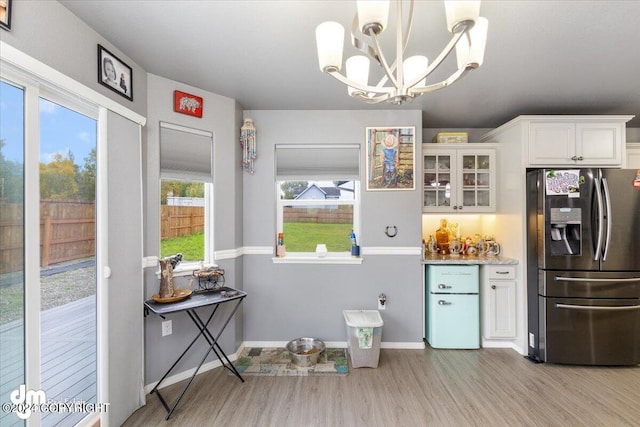 kitchen with stainless steel fridge with ice dispenser, pendant lighting, a chandelier, and white cabinets