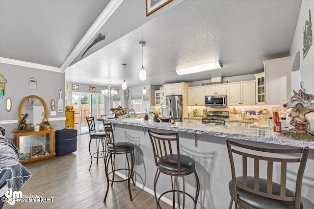 kitchen featuring light hardwood / wood-style flooring, a notable chandelier, appliances with stainless steel finishes, crown molding, and light stone counters