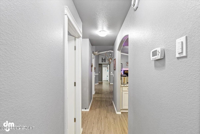 hallway featuring a textured ceiling and light hardwood / wood-style flooring