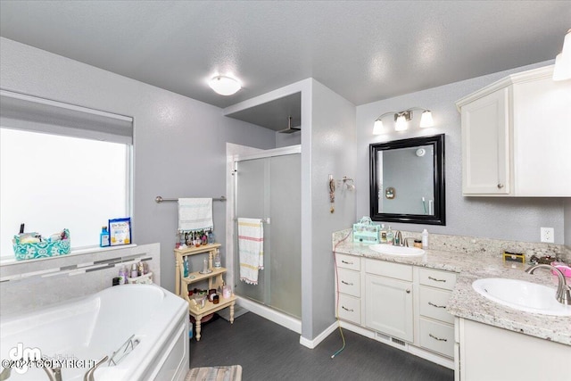 bathroom with a textured ceiling, vanity, and independent shower and bath