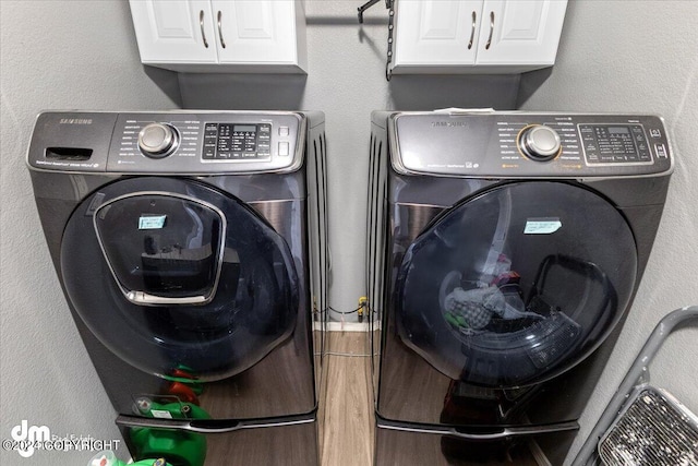 clothes washing area with wood-type flooring, cabinets, and washer and dryer