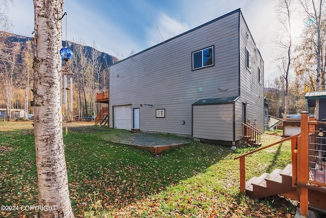 back of house featuring stairs, a yard, a deck with mountain view, and a garage