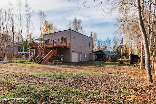 rear view of house with stairs, dirt driveway, a deck, and a garage