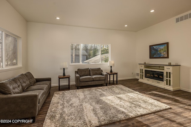 living area with recessed lighting, visible vents, dark wood-type flooring, and a glass covered fireplace