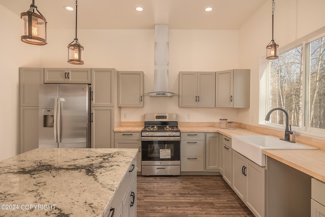 kitchen with pendant lighting, custom exhaust hood, stainless steel appliances, a sink, and light stone countertops