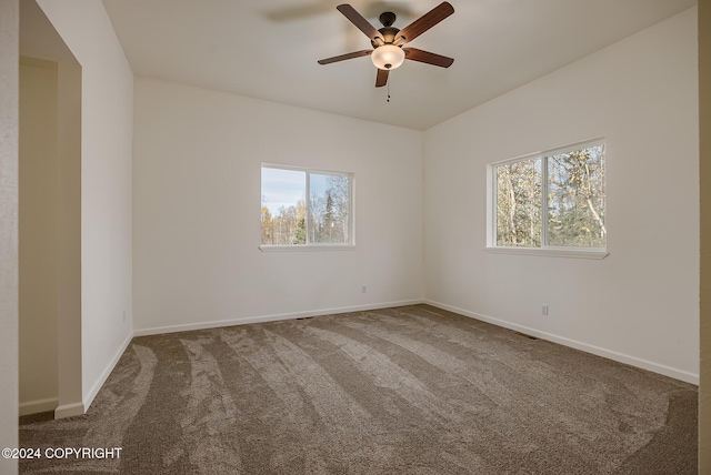 carpeted spare room featuring a healthy amount of sunlight, baseboards, and a ceiling fan