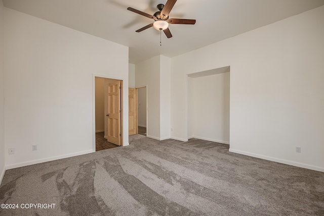 unfurnished bedroom with baseboards, dark colored carpet, and a ceiling fan