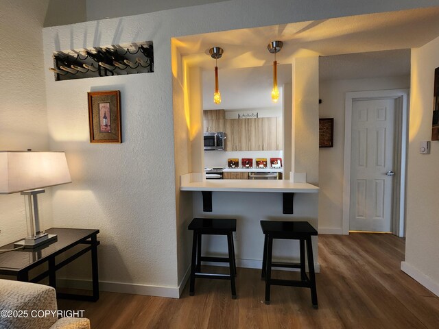 4342 Reka Dr, Anchorage, AK 99508 - kitchen with stainless steel appliances, dark wood-style flooring, a breakfast bar area, a textured wall, and light countertops