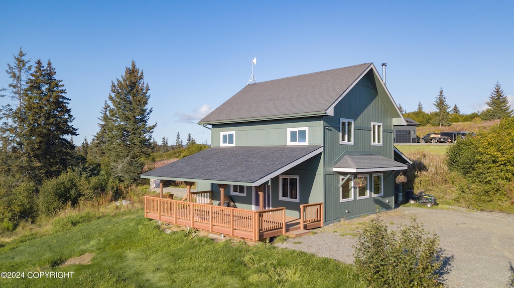 back of property featuring a deck and a lawn