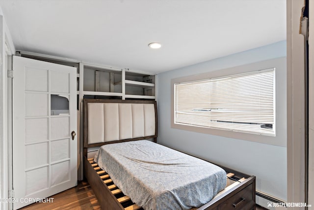 bedroom with baseboard heating and dark hardwood / wood-style flooring