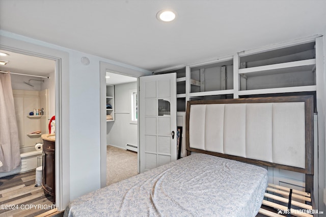 bedroom featuring light hardwood / wood-style floors, connected bathroom, and a baseboard radiator