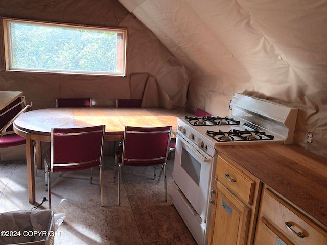 kitchen with vaulted ceiling, white gas range, butcher block countertops, and a healthy amount of sunlight