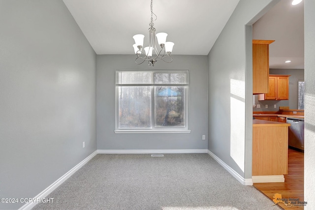 unfurnished dining area featuring carpet flooring and an inviting chandelier