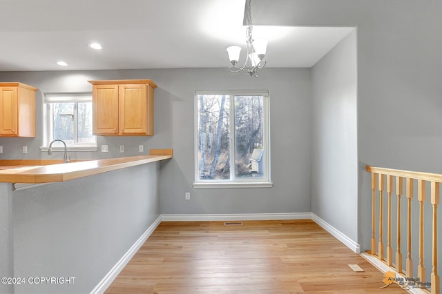 kitchen featuring light hardwood / wood-style floors, light brown cabinets, a chandelier, and pendant lighting