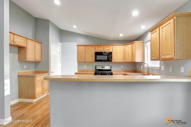 kitchen featuring light brown cabinetry, black appliances, light wood-type flooring, kitchen peninsula, and vaulted ceiling