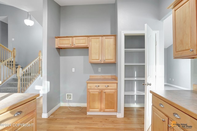 kitchen with light brown cabinetry, light hardwood / wood-style flooring, and hanging light fixtures