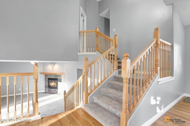 stairway featuring hardwood / wood-style floors, a tile fireplace, and vaulted ceiling