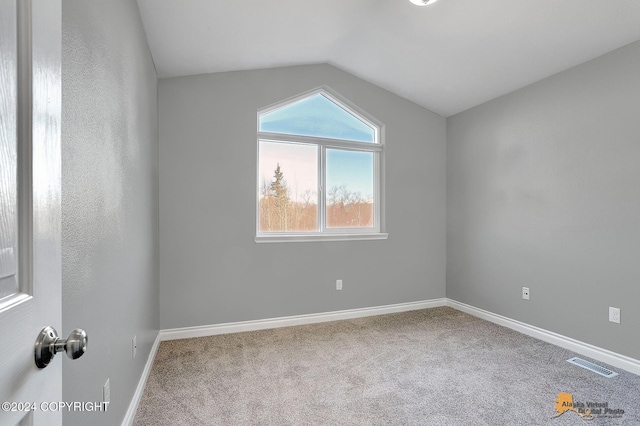 carpeted spare room with vaulted ceiling