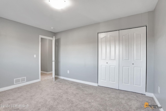 unfurnished bedroom featuring light carpet and a closet