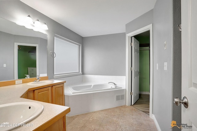 bathroom with vanity, a relaxing tiled tub, and tile patterned flooring