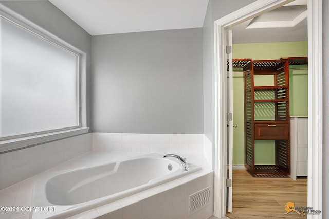 bathroom with wood-type flooring and tiled bath