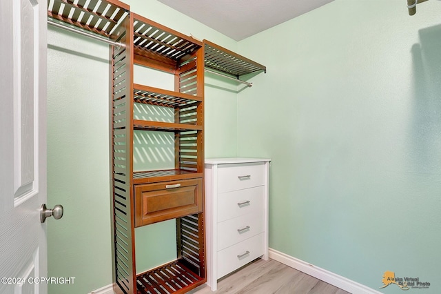 walk in closet with light hardwood / wood-style floors