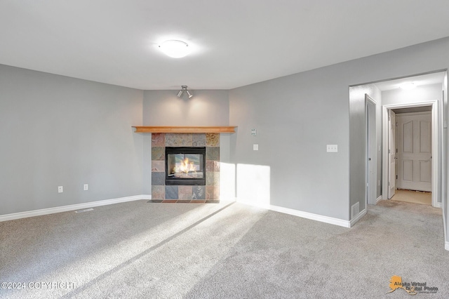 unfurnished living room with light carpet and a tile fireplace