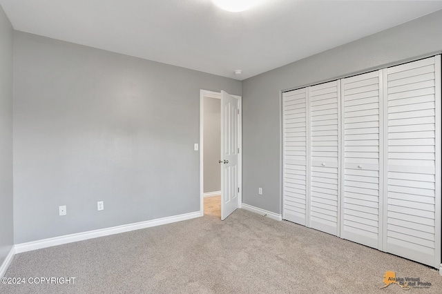 unfurnished bedroom featuring a closet and light colored carpet