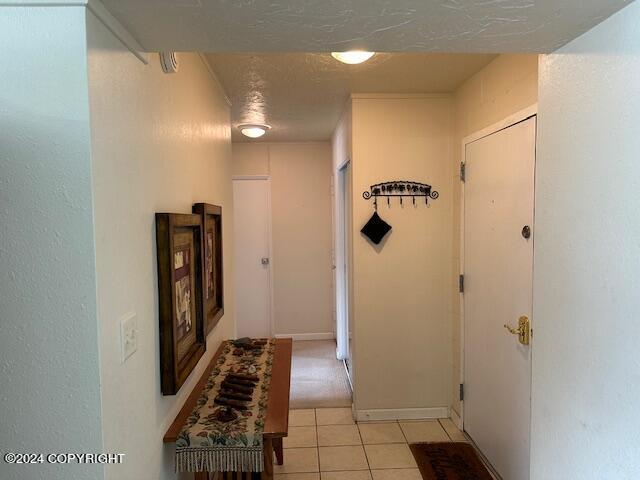 hall with a textured ceiling and light tile patterned floors