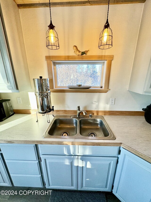 kitchen featuring white cabinetry, sink, and decorative light fixtures