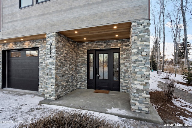 snow covered property entrance with a garage