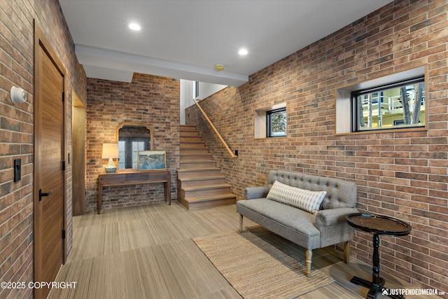 sitting room featuring light colored carpet and brick wall