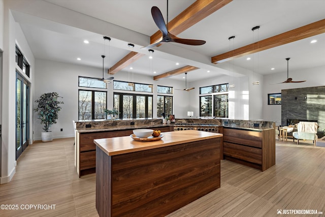 kitchen featuring beam ceiling, decorative light fixtures, ceiling fan, and a spacious island