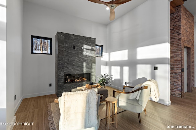 living room with ceiling fan, a high ceiling, and a tiled fireplace