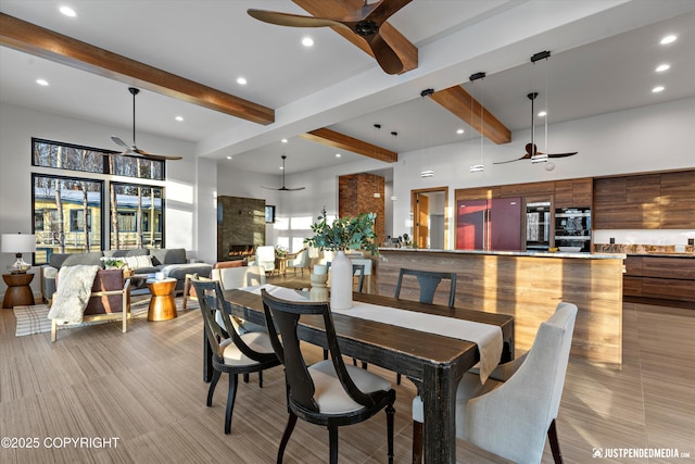 dining space featuring beamed ceiling, ceiling fan, and a towering ceiling