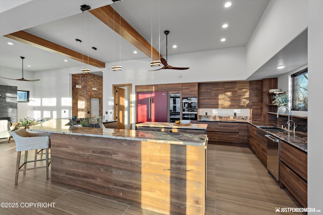 kitchen with a healthy amount of sunlight, sink, hanging light fixtures, and a high ceiling